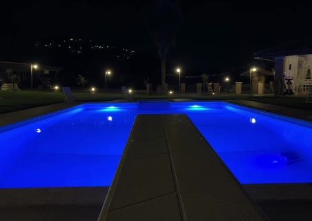La stessa piscina illuminata di blu durante la notte